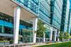 A picture of Birmingham's office in Birmingham. There is a tram route through grass in front of the glass and steel office