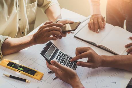 Contractors working on plans with spirit level and calculator